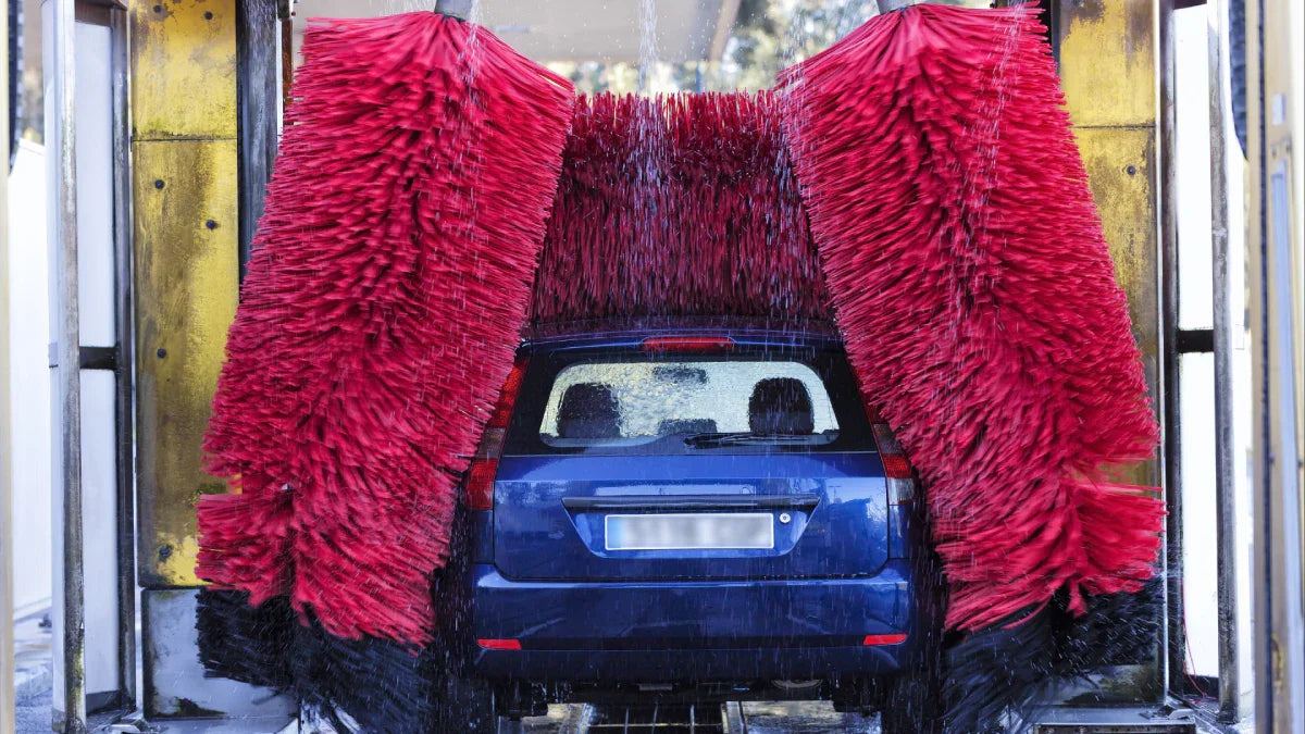 blue car going through a modern soft-touch automatic car wash with blue foam brushes.